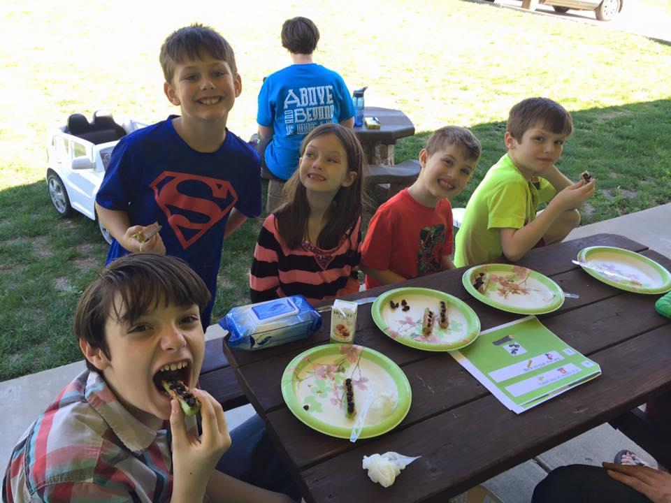 A group of kids eating donuts at the park.