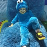 A boy in a cookie monster costume sitting on the couch.