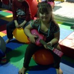 A little girl sitting on the floor playing with a guitar