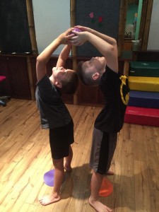 Two young boys are doing a hand stand.