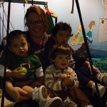 A woman and some kids sitting on a swing