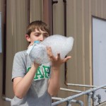 A boy blowing up an object with bubble wrap.