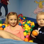 Two children are playing in a ball pit.