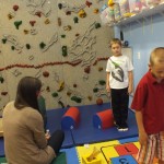 A woman and two boys in front of a wall.