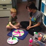 A woman and boy sitting on the floor with paper plates.