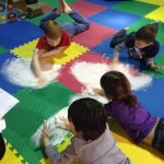 A group of children playing with white sand.