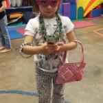 A little girl wearing glasses and holding her cell phone.