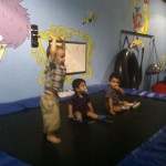 A group of kids sitting on top of an indoor trampoline.