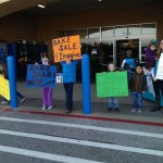 A group of people holding signs in front of a store.