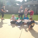 A group of people sitting on the ground with plates.