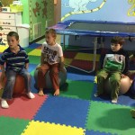 A group of children sitting on top of colorful mats.